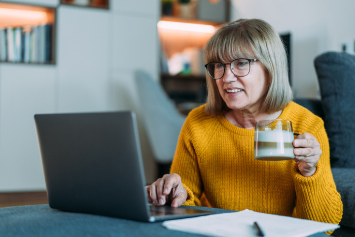 Woman checking her laptop holding a cup of coffee